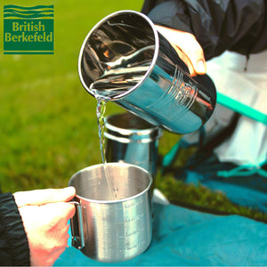 Backpacker pouring purified water into friend's cup from 1L Adventure British Berkefeld stainless steel gravity filter.