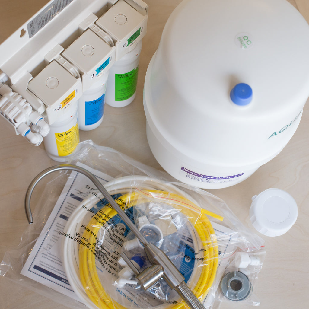 AquaTru Undersink Water Purifier components showing filter manifold storage tank tubing fittings and included faucet.
